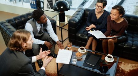 High angle portrait of group of successful business people meeting over coffee table in luxury office